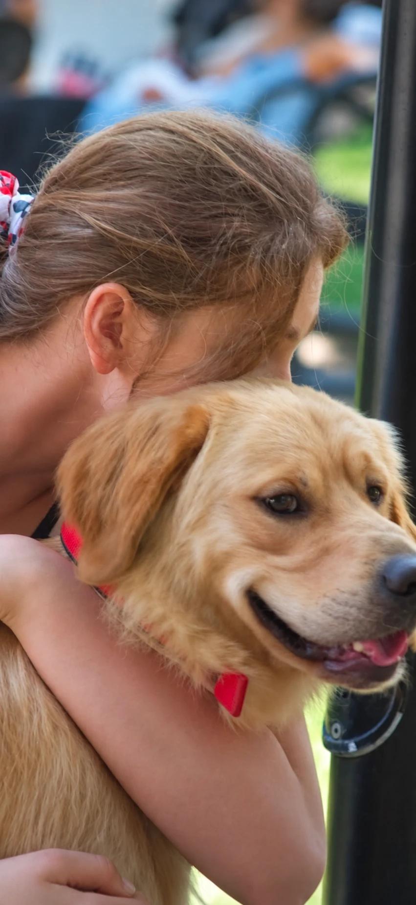 A childhood photo of a girl cuddling a golden retriever