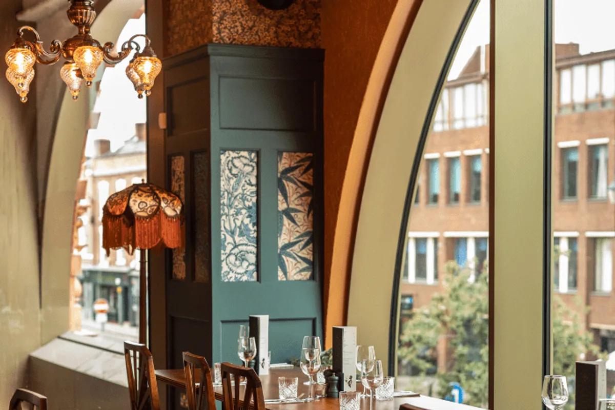 Dining tables and tall arched windows inside Cosy Club Chester