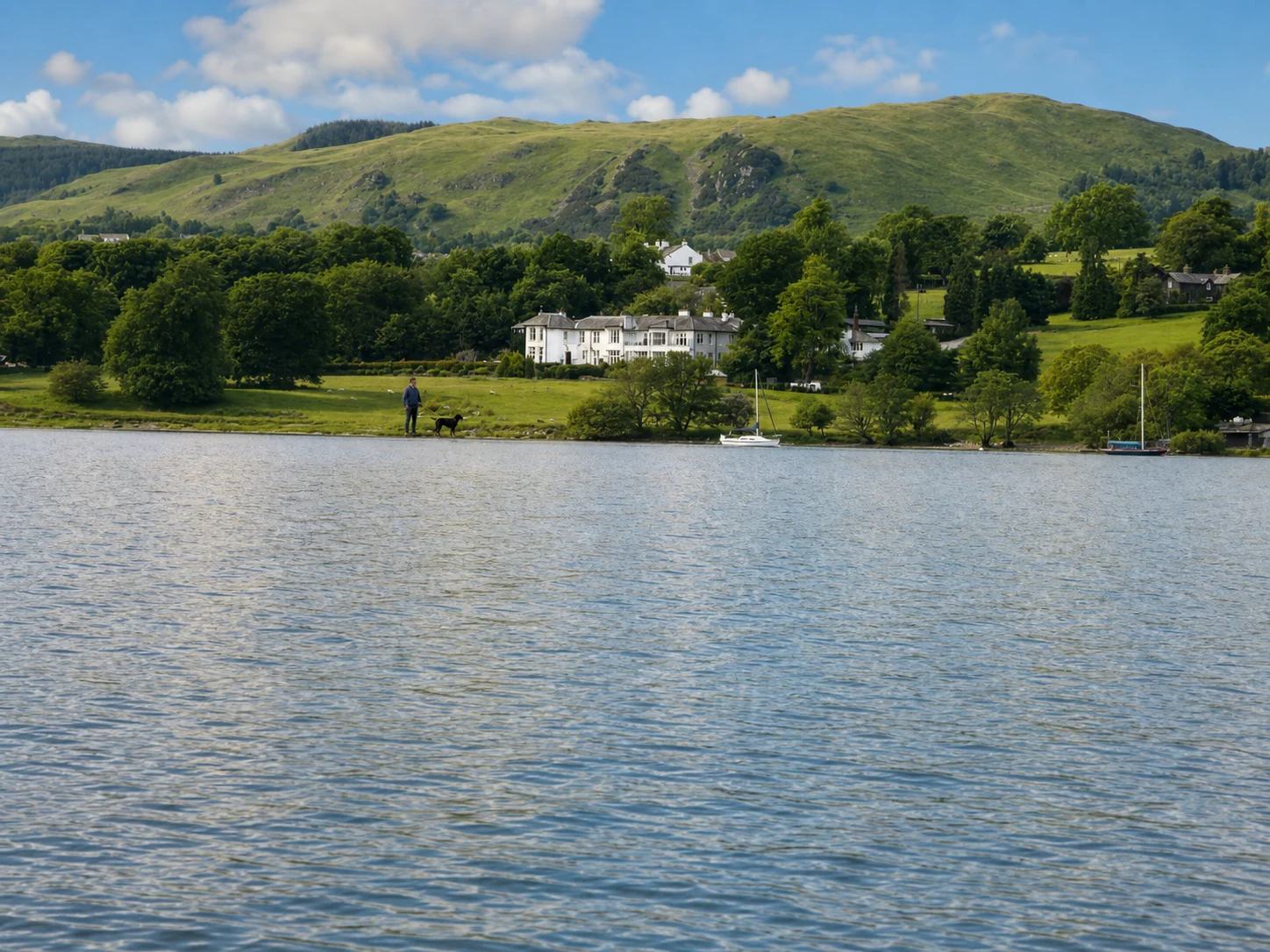 A guest and black Labrador beside Ullswater with Another Place and green fells beyond