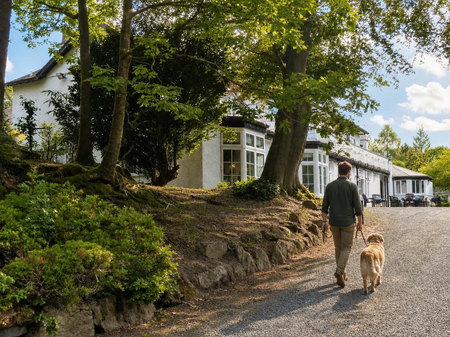 A guest and golden retriever arriving at Rothay Manor through its garden trees