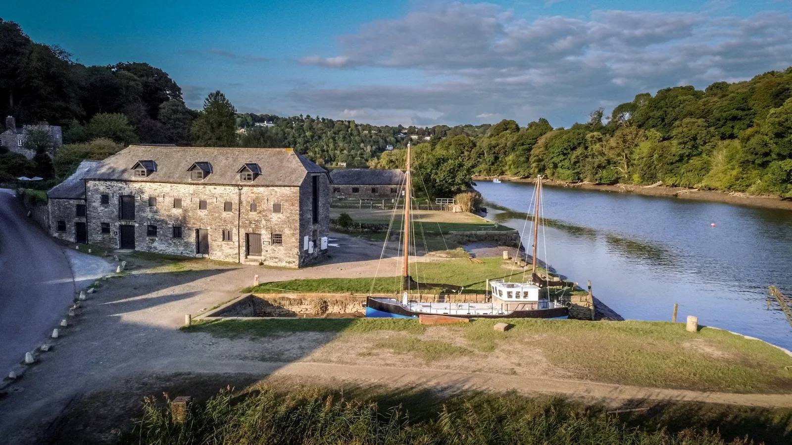 Historic buildings and a boat beside the River Tamar at Cotehele Quay