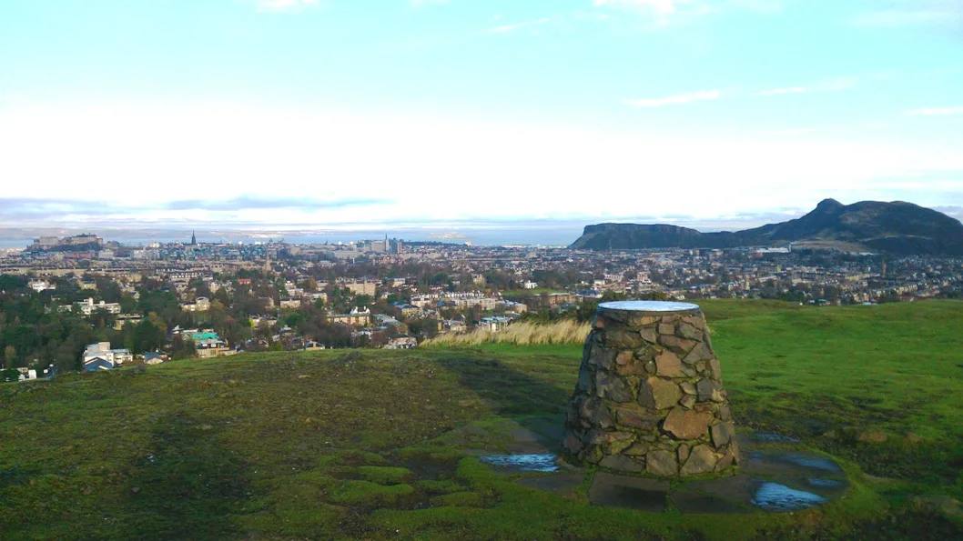 The summit marker on Blackford Hill with Edinburgh beyond