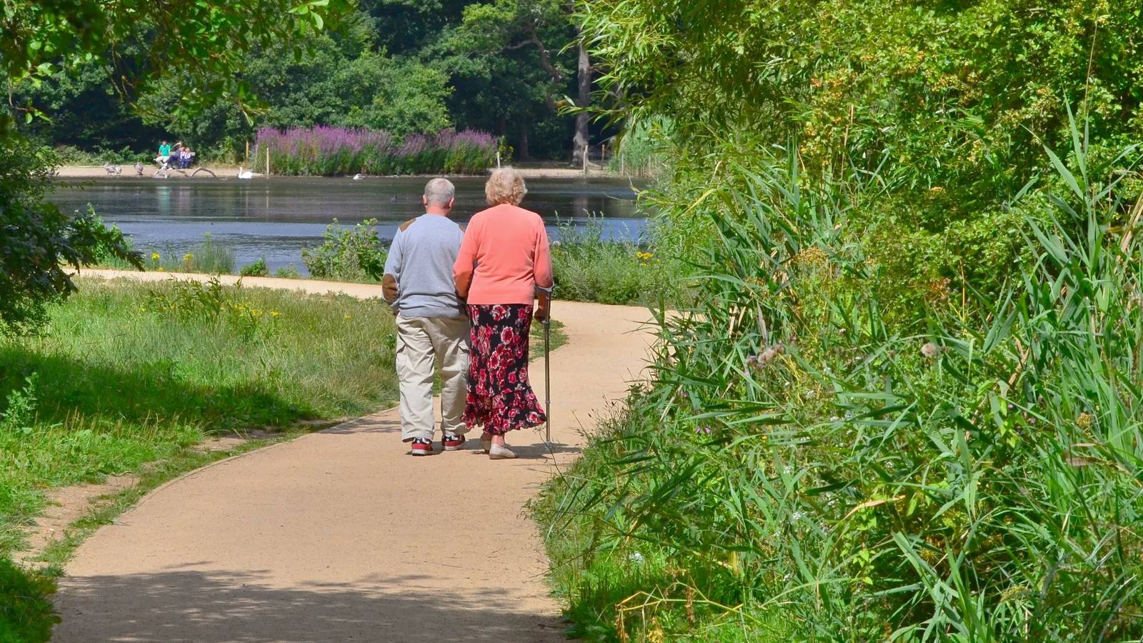 Two people walking beside Connaught Water in Epping Forest