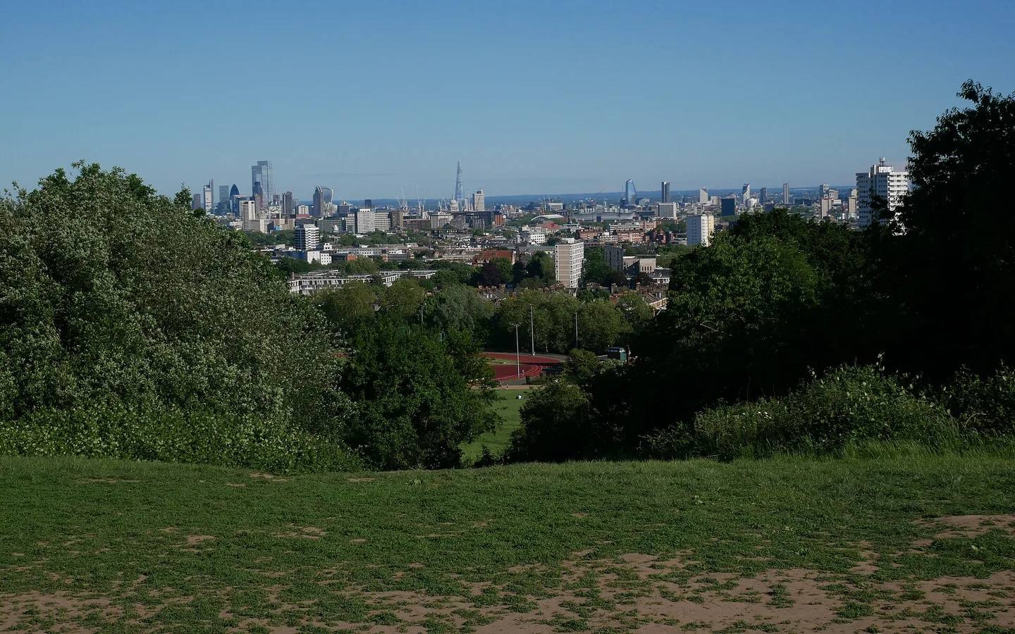 London skyline viewed across the grass and trees from Parliament Hill