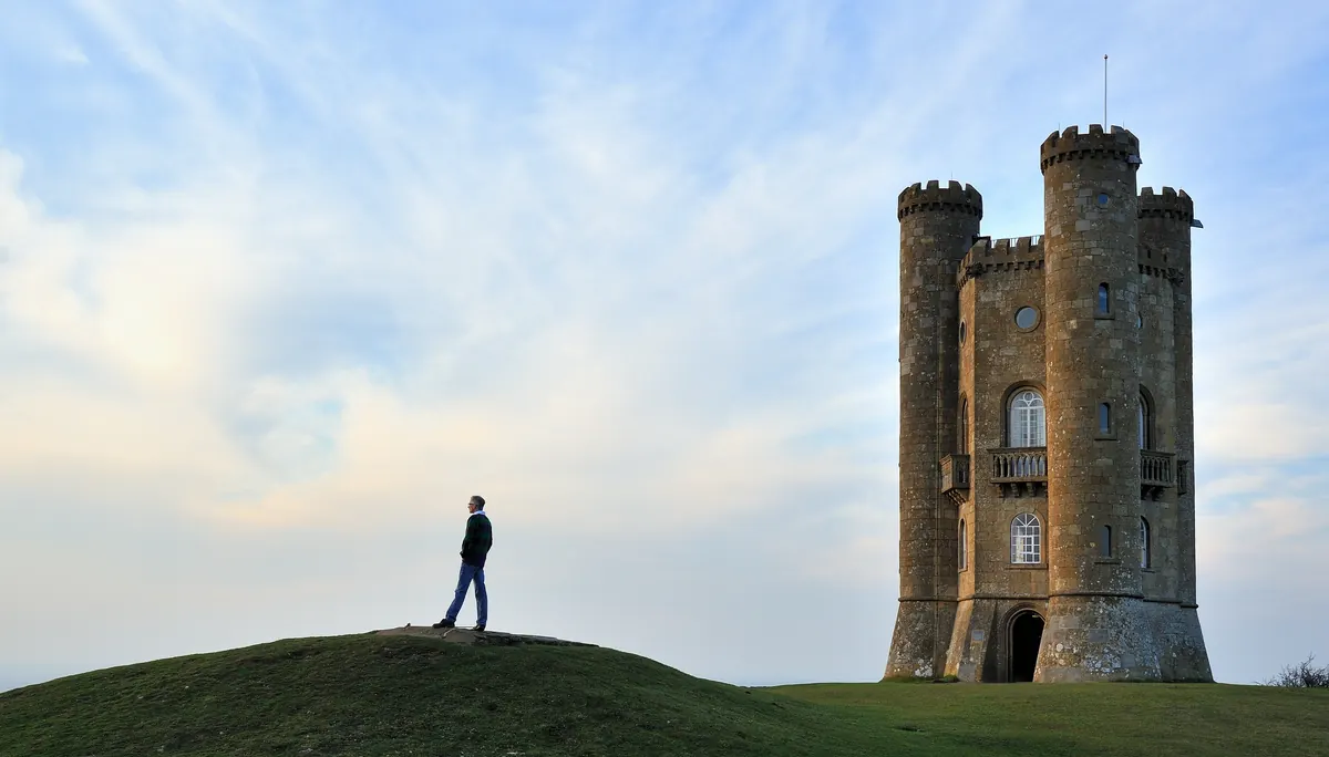 A walker beside Broadway Tower on a route published by Dormy House