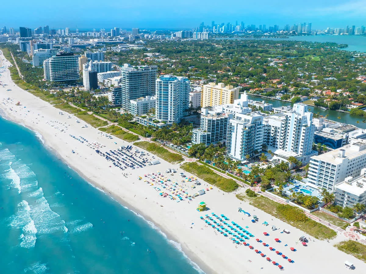 Aerial view along Miami Beach's Mid Beach shoreline and oceanfront buildings.