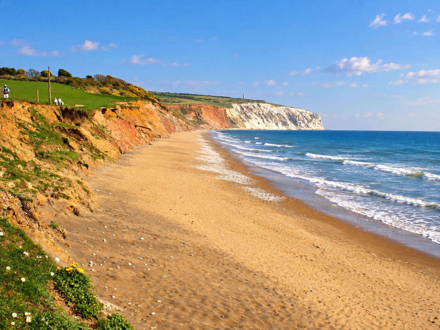Sunlit Yaverland Beach below the red cliffs and white Culver Down headland, an area overview