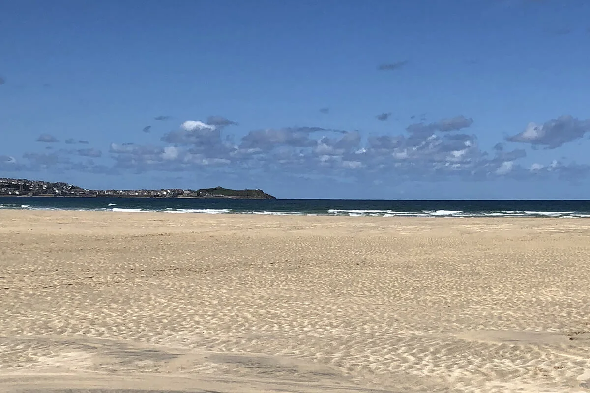 Porth Kidney's wide sand and distant St Ives shoreline.
